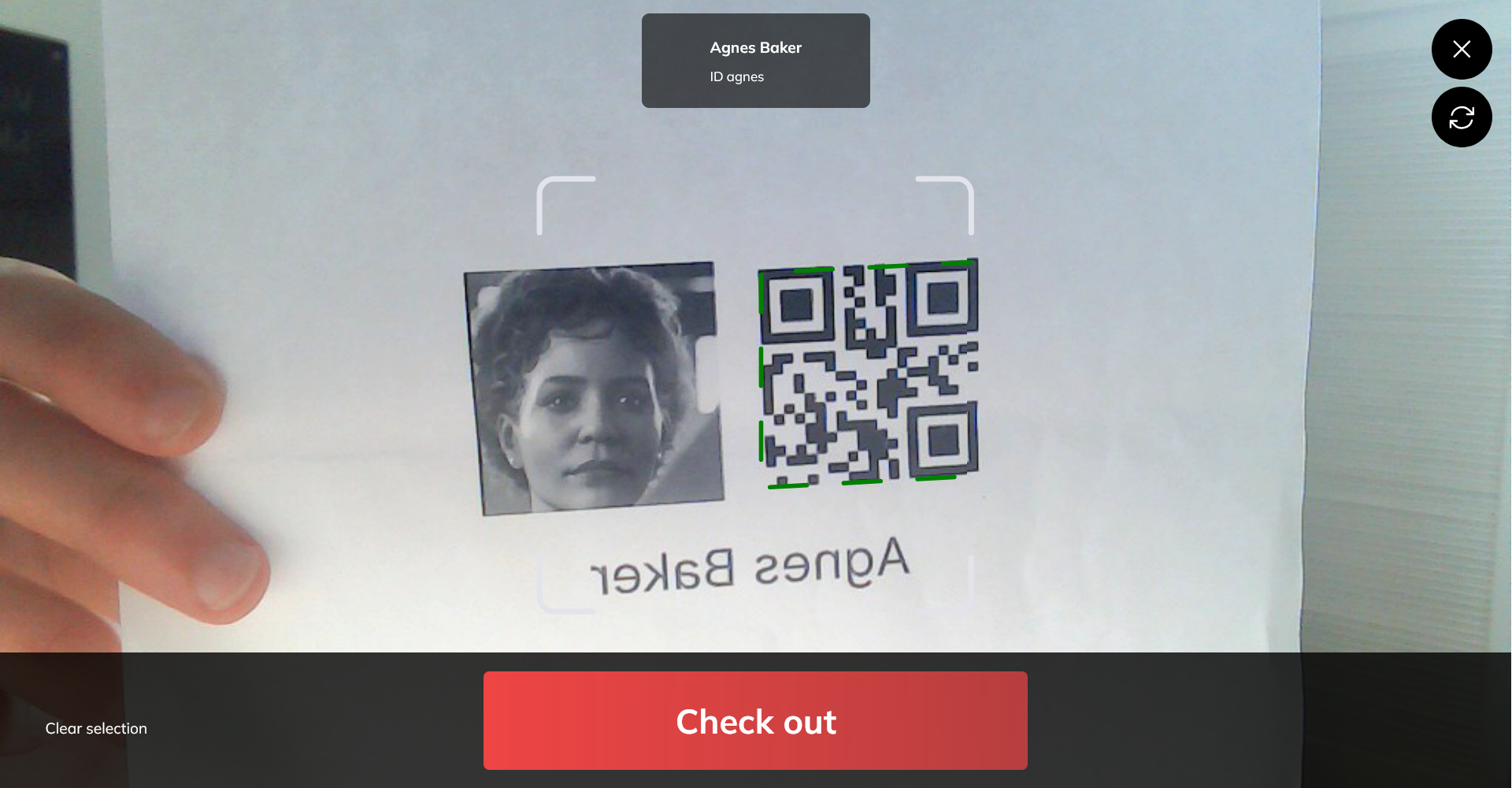 The camera view scanning a printed badge, with the matched person's name at the top and a red Check out button across the bottom.